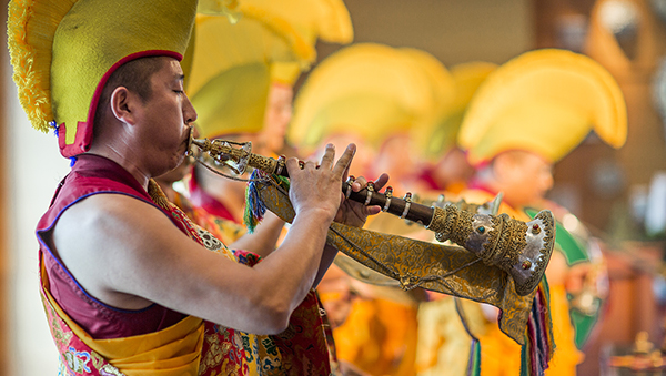 monk blowing a Tibetan horn